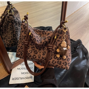 Close-up of leopard print tote bag with brown velvet charm and gold hardware accents