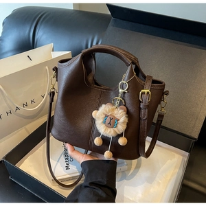 Detail of dark brown leather handbag with adjustable strap and cute plush bear charm