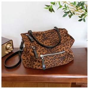 Détail du sac cabas léopard avec poignées en cuir noir et bandoulière réglable