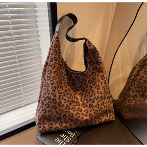 Close-up of leopard print hobo bag with black leather strap on a reflective surface
