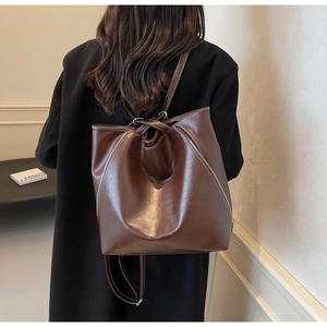 Rear view of a model wearing a retro dark brown leather backpack with white stitching