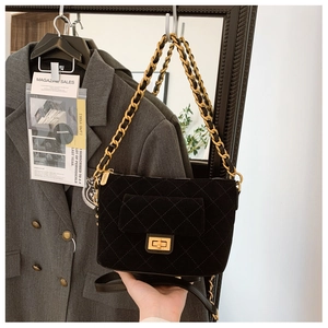 Detail of black quilted crossbody bag with gold twist lock and velvet texture finish