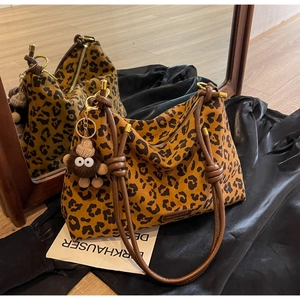 Detailed view of leopard print tote bag with brown knotted rope strap and plush charm