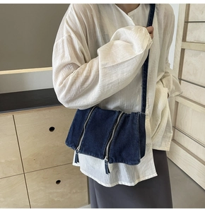 Detailed view of dark blue denim tote bag with silver zippers and shoulder strap