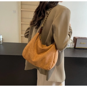 Detail view of brown matte leather hobo bag with chain strap worn with a beige blazer