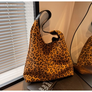 Close-up of leopard print hobo tote bag with black leather strap in cozy indoor setting