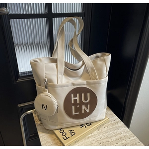 Detail of canvas tote bag with brown leather HULN logo patch and round coin purse