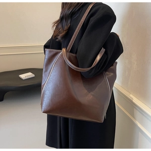 Detail of deep brown tote bag featuring white contrast stitching and side zippers