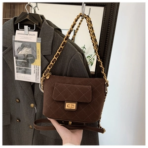 Detail of dark brown quilted suede bag with gold chain strap and elegant metal turn-lock