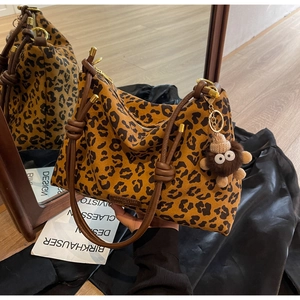 Detail of leopard print tote bag featuring a thick brown rope handle and plush pendant