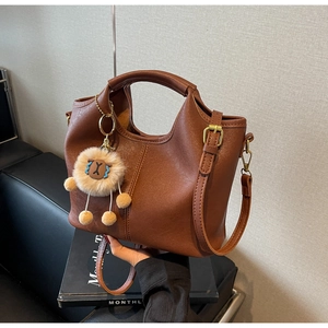 Brown lychee texture handbag with matching shoulder strap and lion plush charm accessory