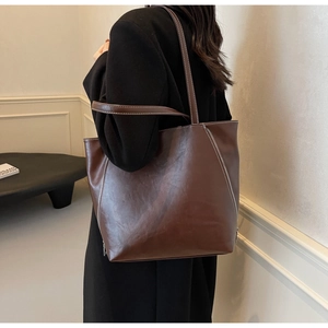 Detail of dark brown tote bag showing decorative zippers and contrast stitching craft