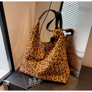 Detailed view of large leopard print tote bag with black leather strap on studio background