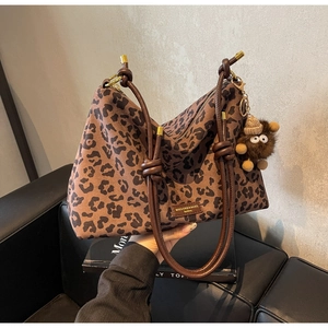 Detail of leopard print tote bag with knotted handles and plush monster keychain