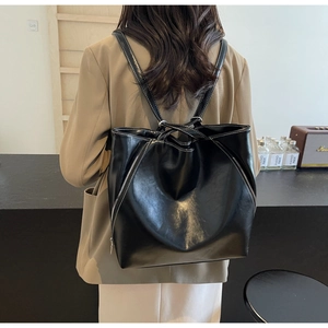 Detail of a vintage black leather backpack with white stitching and long zipper decor