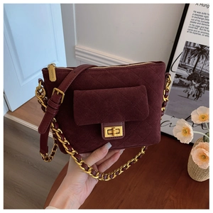 Macro view of burgundy quilted suede texture with golden chain strap and metallic lock