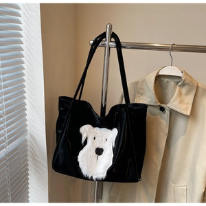 Detail of black tote bag with white plush dog patch on shiny high-density fabric