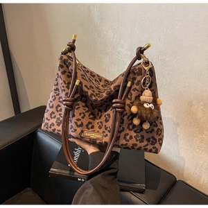 Detail of leopard print tote bag with gold metal logo and brown plush monkey charm