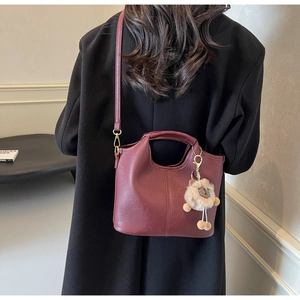 Deep burgundy leather handbag with crossbody strap and cute plush sheep charm detail