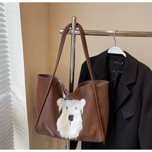 Close-up of brown faux leather tote bag with cute plush animal patch and double straps