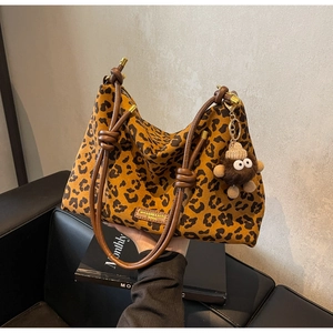 Detail of leopard print tote bag with brown knotted strap and plush charm on suede fabric