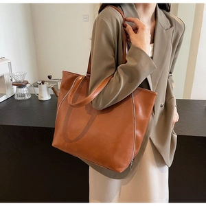 Brown large capacity leather tote bag with decorative zippers and contrast stitching
