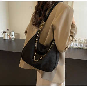 Detail of matte black suede crossbody bag featuring gold chain and thin shoulder strap