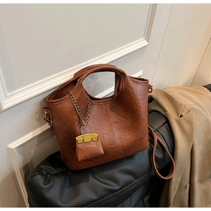 Gros plan du sac seau marron en cuir avec texture litchi et mini pochette décorative