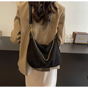 Close-up of matte black hobo bag with gold chain strap shown on model from behind
