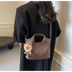 Deep brown matte leather tote bag with lion plush pendant shown on fashion model