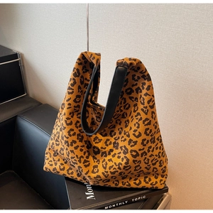 Detail shot of leopard print tote bag with black wide leather straps on a stylish sofa