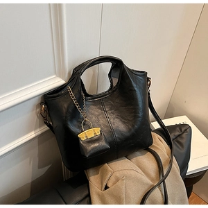 Détail du sac seau rétro en cuir noir avec chaîne dorée et mini pendentif décoratif