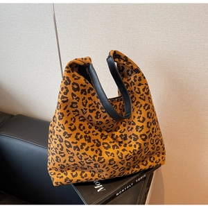 Detailed view of leopard print tote bag with black wide handle on leather sofa