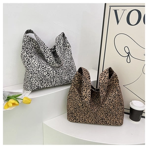 Close-up of leopard print canvas tote bags in white and brown on a minimalist display