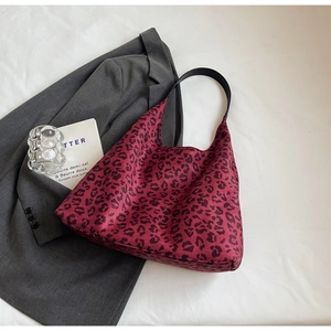 Detail of red leopard print tote bag with black strap on stylish suit background