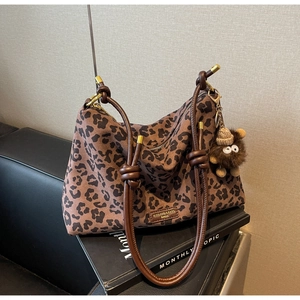 Detail view of large leopard print tote bag with brown leather straps and metal hardware