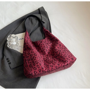 Detail of burgundy leopard print tote bag placed on a grey blazer for a chic look