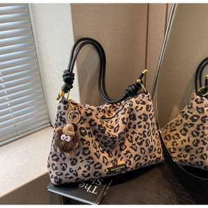 Close-up of leopard print tote bag with plush monster charm and knotted rope handles