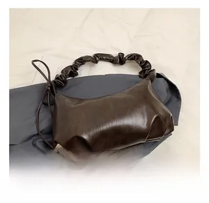 Détail macro du sac croissant plissé marron foncé avec bandoulière à volants bouffants