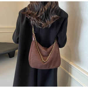 Brown frosted suede hobo bag with gold chain strap shown on model in a minimalist setting