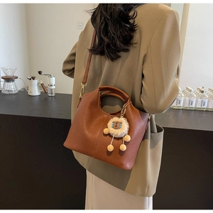 Brown vintage faux leather tote bag with a cute plush sheep charm in a cafe setting