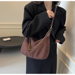 Detail of a brown matte suede shoulder bag featuring a gold woven chain and leather strap