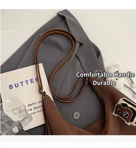Detail of a brown crescent tote bag with a plush B patch on a grey suit jacket