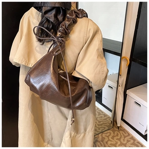 Détail d'un sac à plis marron foncé montrant la texture douce et le nœud décoratif