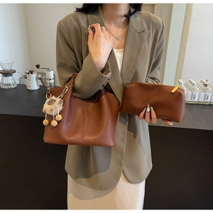 Detail of vintage brown pebble leather tote bag set with metal chain and plush charm