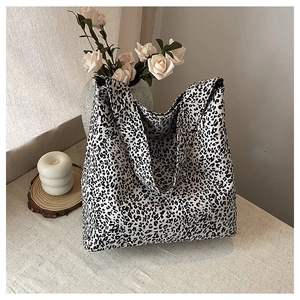 Detailed view of large leopard print canvas tote bag on a minimalist styled beige surface