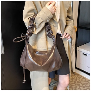 Détail du sac demi-lune marron foncé avec bandoulière froncée et texture souple plissée