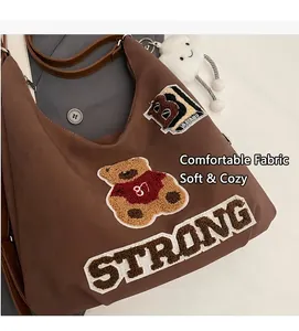 Detail of dark brown tote bag featuring bear embroidery and plush cloud charm