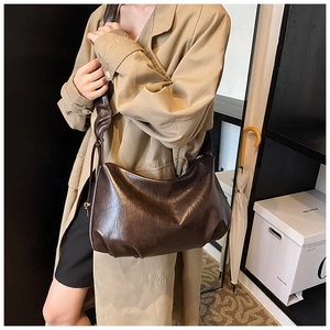 Détail d'un sac hobo en cuir marron foncé avec texture plissée et large bandoulière
