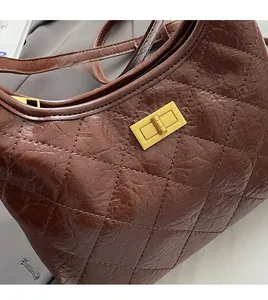 Dettaglio della pelle trapuntata marrone scuro e chiusura dorata vintage della borsa